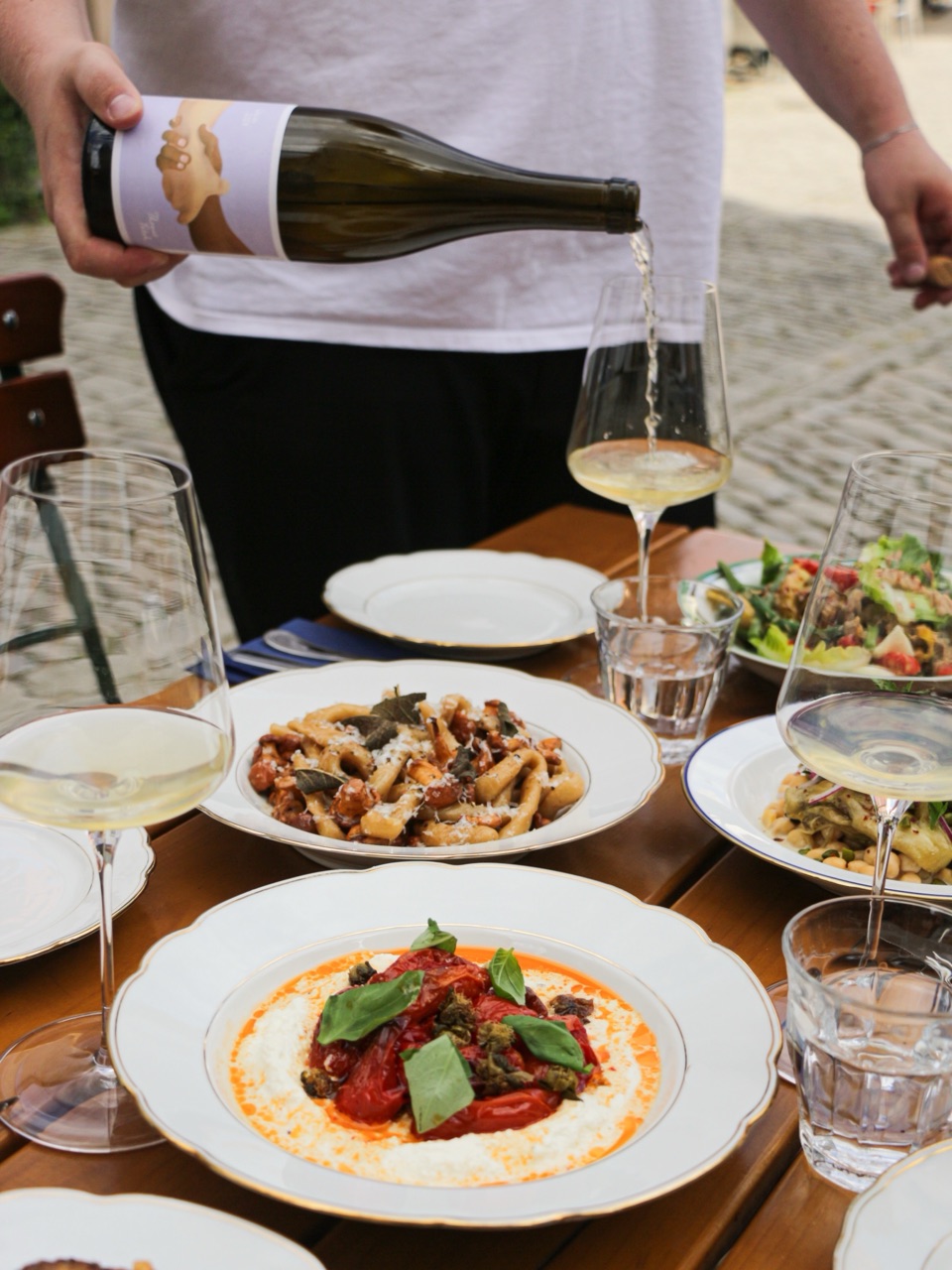 Pasta und Tomaten mit einem Glas Weißwein am Holztisch