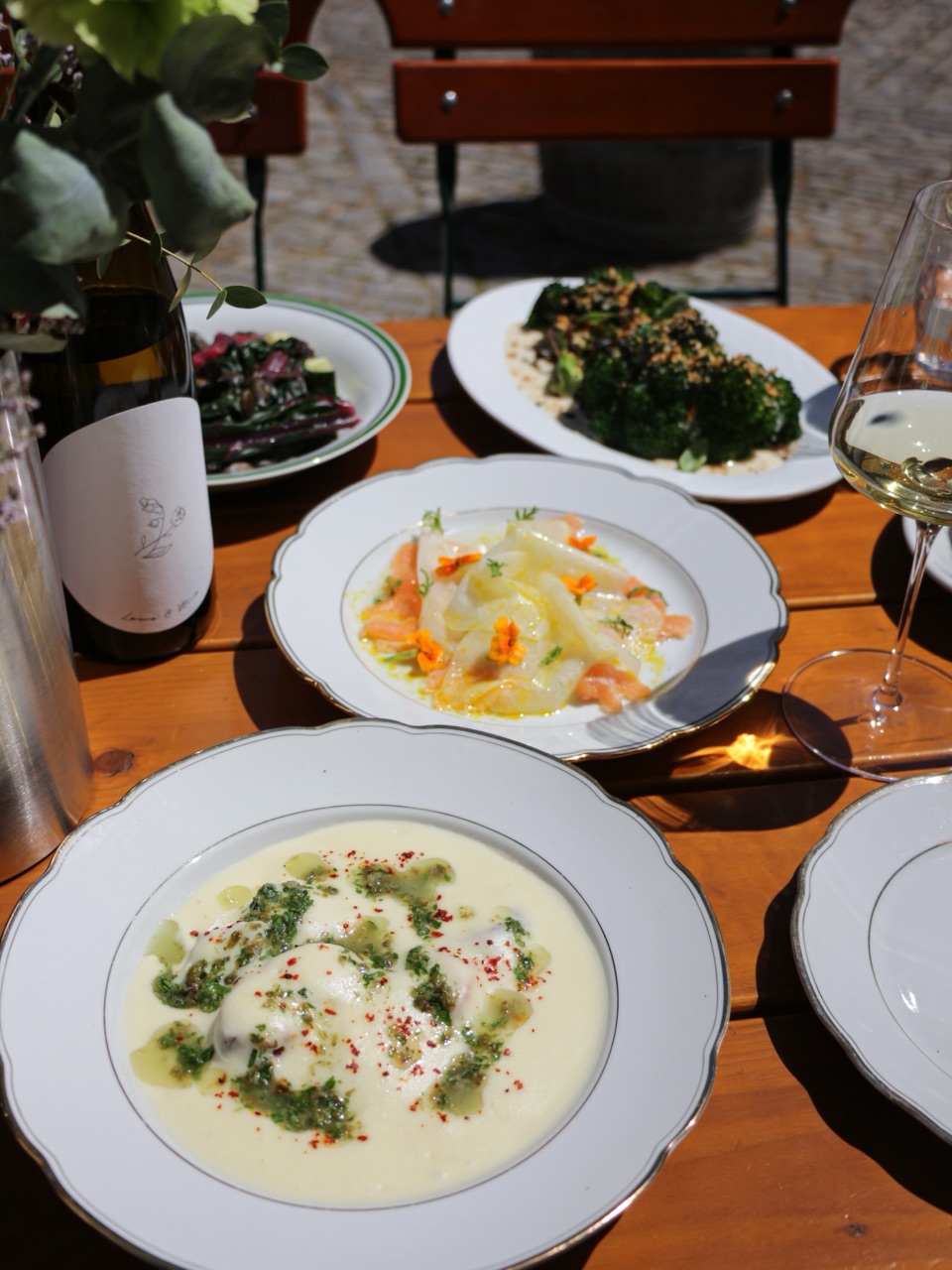 Cremige Suppe mit Kräuteröl, dahinter weitere Gerichte